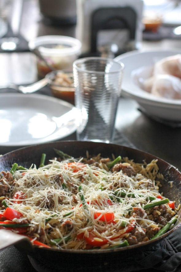 Orzo with sauage in a skillet.